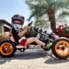 Child riding a pedal-powered tricycle with helmet outdoors.