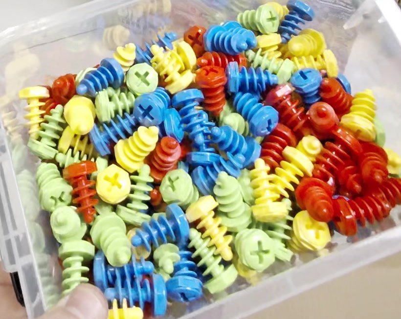 The kit's red, blue, yellow and green plastic screws in their clear storage box