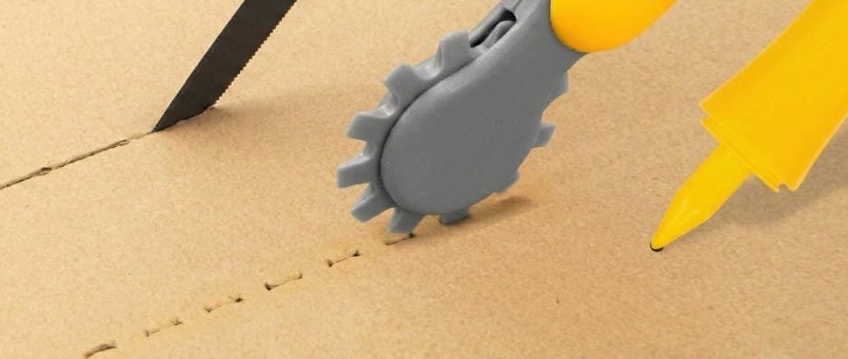 Cardboard saw, scoring wheel and hole punch working on a sheet of cardboard