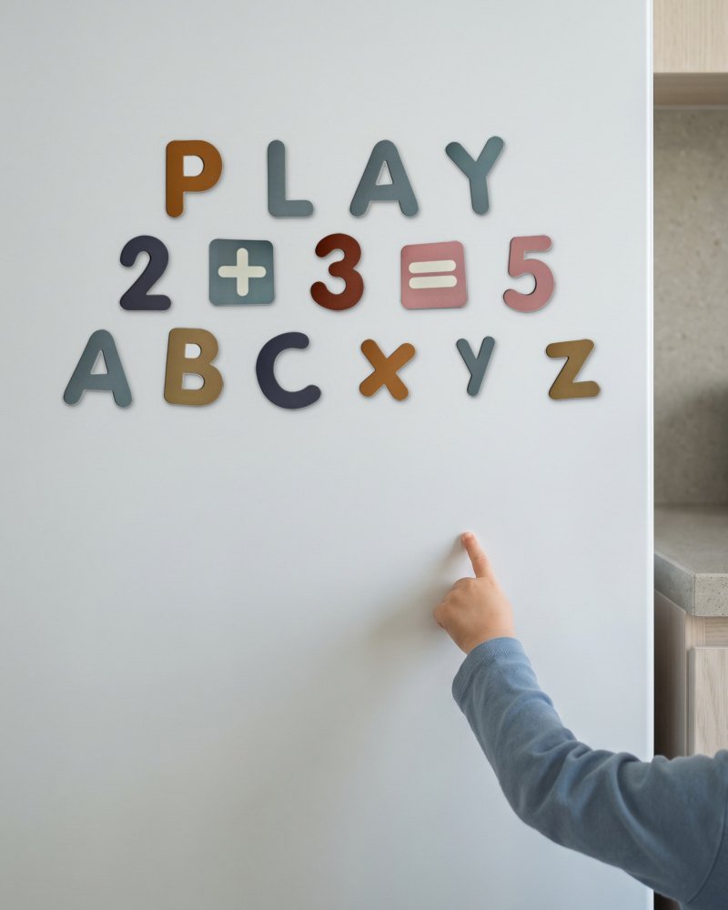 A child's hand placing a magnet on a white fridge door